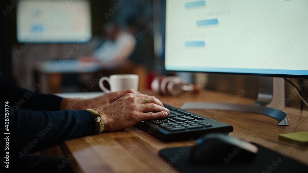 Poster Close Up on Male Hands of a Specialist Working on Desktop Computer in a Busy Creative Office Environment. Manager First Types on a Keyboard and Then Uses the Mouse. He's Wearing a Craft Bracelet.