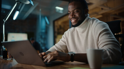 Handsome Black African American Man Having an Online Conversation on a Laptop Computer in Creative...