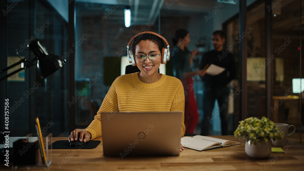 Poster young hispanic project manager in headphones and working on laptop computer in busy creative office 