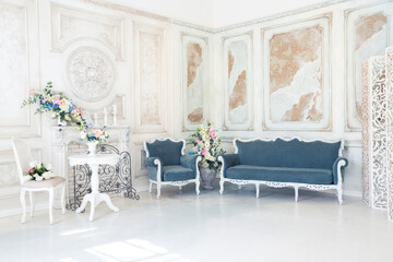Bright luxury white and blue colored interior living room with flowers in vases. the walls are decorated with baroque ornaments