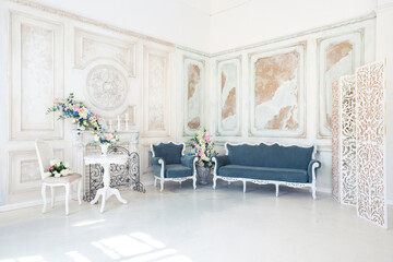 Bright luxury white and blue colored interior living room with flowers in vases. the walls are decorated with baroque ornaments