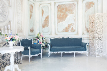 Bright luxury white and blue colored interior living room with flowers in vases. the walls are decorated with baroque ornaments