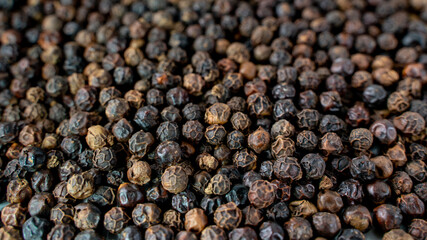 Black pepper grains as background close up.