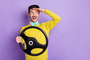 Portrait of brunet impressed guy hold wheel look far wear yellow sweater isolated on pastel lilac color background