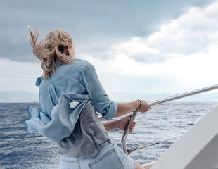 Woman on yacht holding tight during storm in the sea.