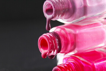 drops of red bearded pink nail polish flow from the bottle of the bottle on a black dark background with a copyspace