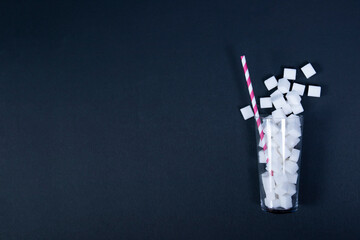 Glass with straw full of sugar cubes - unhealthy diet concept.