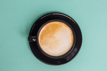 Black cup of coffee on a turquoise background. Place for logo