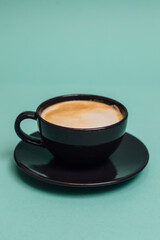 Black cup of coffee on a turquoise background. Place for logo