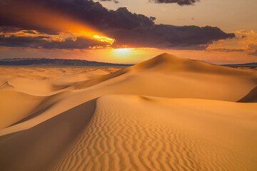 Fototapeta na wymiar Sunset over the sand dunes in the desert. Arid landscape of the Sahara desert