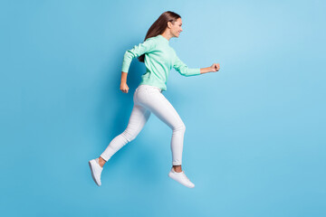 Fototapeta na wymiar Full length profile photo of purposeful lady girl wear casual outfit jumping high hands fists isolated blue color background