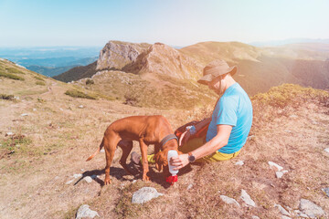 Adventurous Man Hiker and dog are taking a rest at the top of the mountain with great view