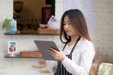 Young Asian woman holding tablet. Business owner coffee shop take order with technology concept.