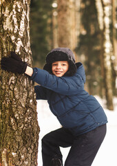 Boy climbs a tree in winter in the woods