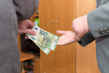Hand giving euro cash like bribe or tips hard worked hand taking 100 euro banknotes.