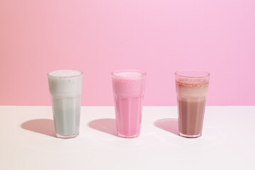 Strawberry, chocolate and vanilla milkshake with whipped cream on pink background. Place for text. Sweet drinks - 408763767