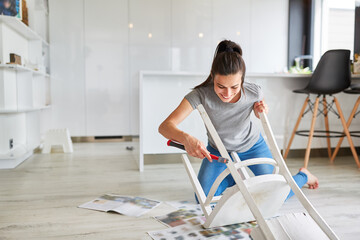 Handyman woman painting chair at home