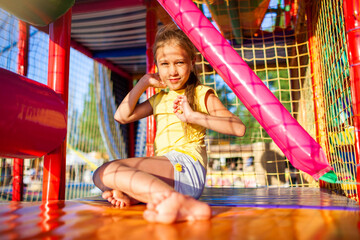 Funny tear-stained girl sits on a rug and wipes her tears in an entertainment center with colorful...