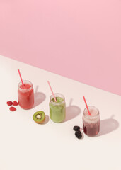 Summer colorful fruit smoothies in jars on pink background. Healthy, detox and diet food concept. Copy space