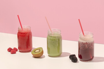 Summer colorful fruit smoothies in jars on pink background. Healthy, detox and diet food concept. Copy space