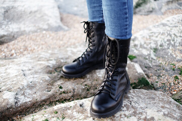 Legs in black boots and jeans in the rocky mountains, a girl on an expedition on outdoor activities