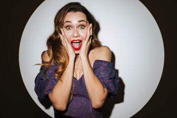 Delighted beautiful girl in evening dress expressing surprise on camera