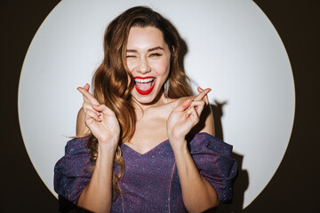 Funny girl winking while posing with fingers crossed for good luck