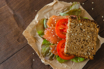 Redfish sandwich with salad and tomatoes laying on a kraft paper