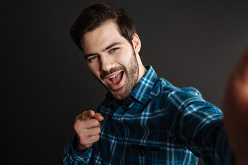 Fototapeta premium Joyful handsome brunette guy pointing finger at camera