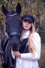 Portrait of a teenage girl , hugging a Chestnut horse against the background of an autumn forest.