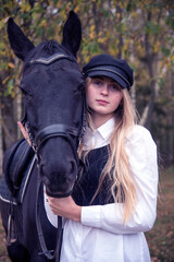 Fototapeta premium Portrait of a teenage girl , hugging a Chestnut horse against the background of an autumn forest.