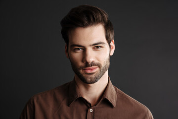 Pleased handsome unshaven guy posing and looking aside