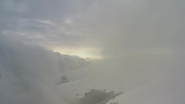 Snowstorm and clouds on top of the mountain. Aerial view.