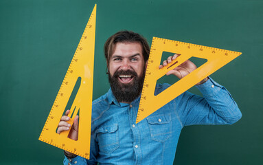 measure and size. happy mature teacher holding triangle tool. bearded man work in classroom with...