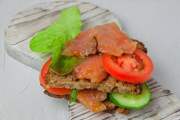 Redfish bread snack with salad, vegetables and herbs laying on a white rustic board