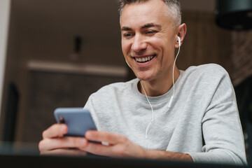 Close up of a smiling man listening to music with earphones