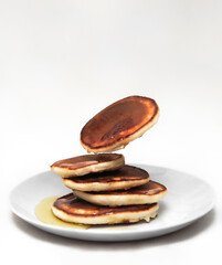Flying pancakes pile with honey on white background