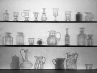 View of different shaped glasses and bottles silhouettes through fabric 