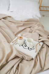 cups with coffee on a tray on a white bed in the bedroom