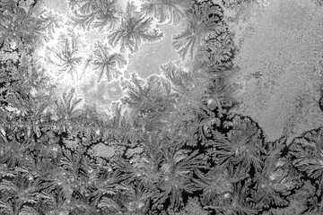 gray texture of frost ice surface with frozen design tracery on a window glass ,black and white cryslallized surface background , abstract macro wallpaper