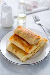 Served breakfast table with stuffed pancakes on a white plate, selective focus