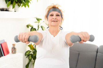 Fototapeta na wymiar Senior woman doing physical exercises with a dumbbell