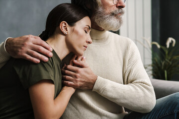 Serious mature father hugging and holding his military daughter's hand