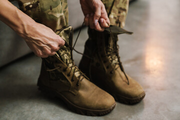Soldier woman tying her shoe laces while sitting on couch indoors