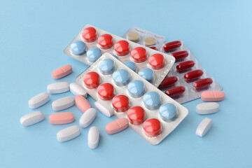 Assorted pharmaceutical medicine pills, tablets and capsules over blue background