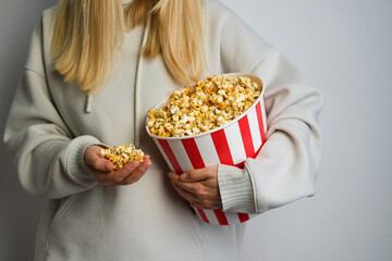 Popcorn paper bucket in the hands of a young girl preparing to watch a movie. Showtime. Eating...