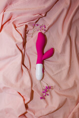 Silicone pink dildo vibrator on bed