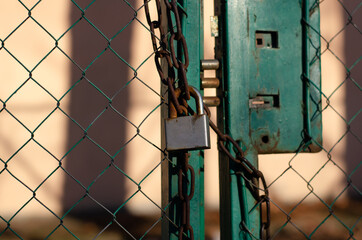 Padlock. Steel chain. Closed gate. Metal grid.