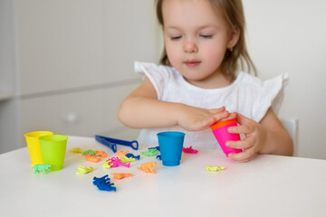 Toddler learns colors. A little girl sorts the animal figures by color, throwing them into the appropriate cup. Development of fine motor skills.