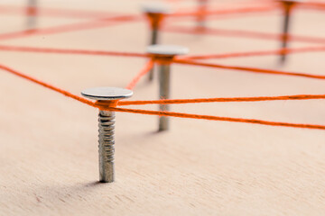 threads and nails on a wooden board.